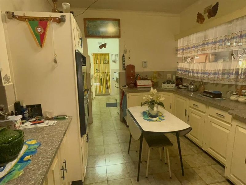 A dated kitchen featuring built-in cabinetry, laminate countertops, and tiled flooring, offering potential for a modern renovation to enhance functionality and aesthetic appeal.