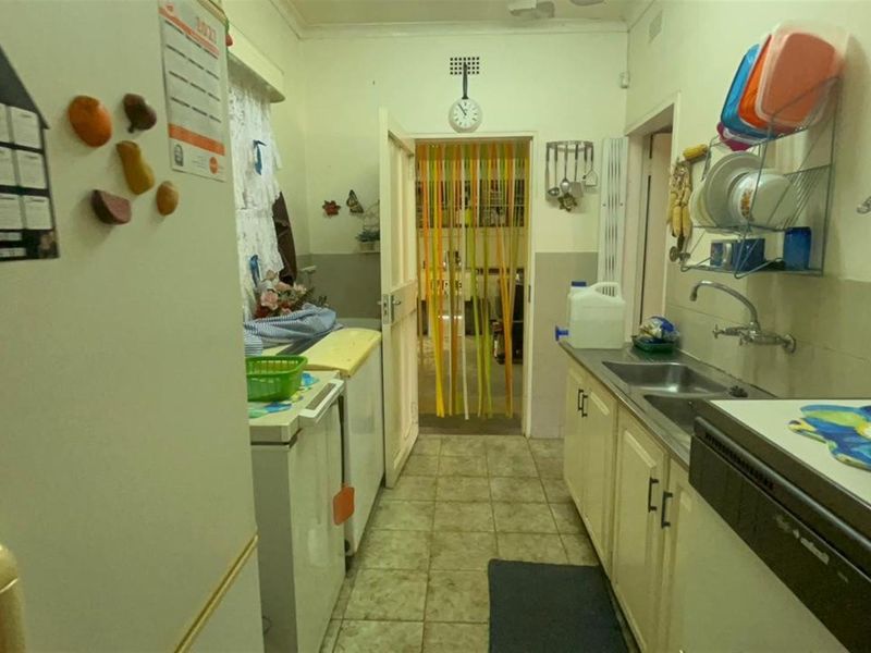 A functional scullery area featuring a stainless steel sink, built-in cabinetry, and tiled flooring, providing additional prep and wash-up space.