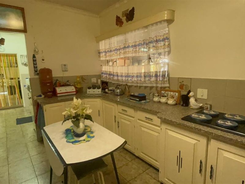 A functional kitchen featuring built-in cabinetry, laminate countertops, and a built-in electric hob, offering a dated aesthetic ready for modernization.