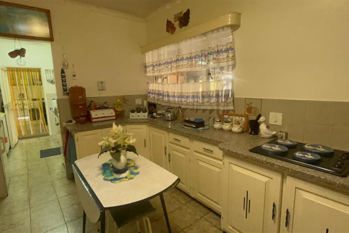 A functional kitchen featuring built-in cabinetry, laminate countertops, and a built-in electric hob, offering a dated aesthetic ready for modernization.