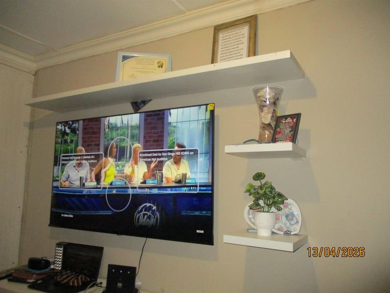 A living room wall featuring mounted floating shelves and decorative coving.