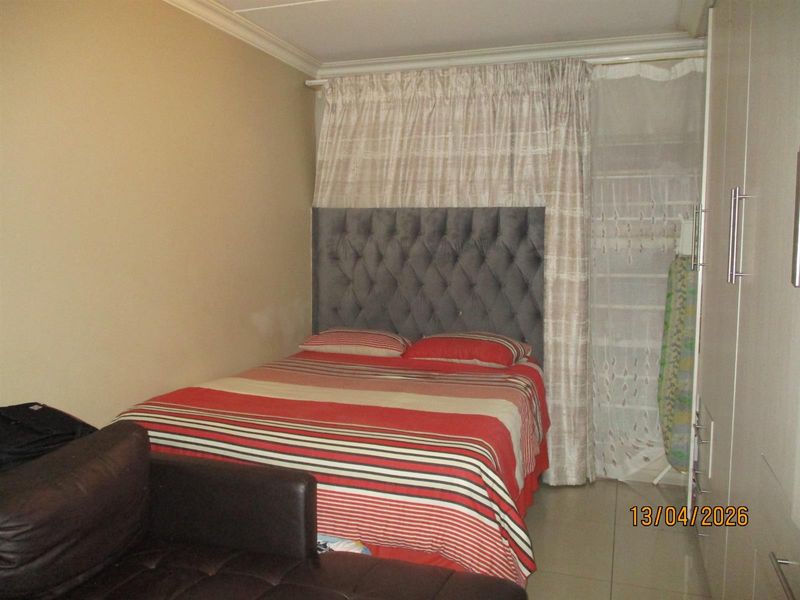 A compact bedroom featuring tiled flooring, a built-in wardrobe, and coved ceiling details.