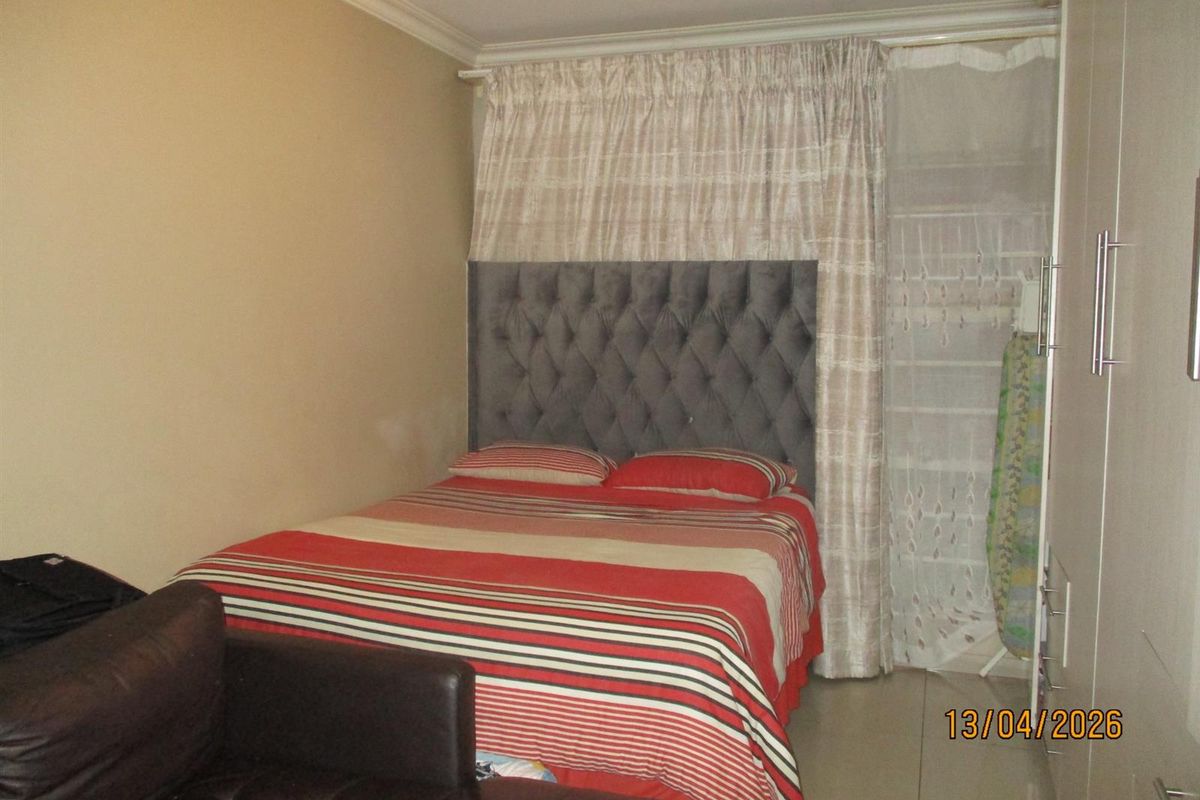 A compact bedroom featuring tiled flooring, a built-in wardrobe, and coved ceiling details.