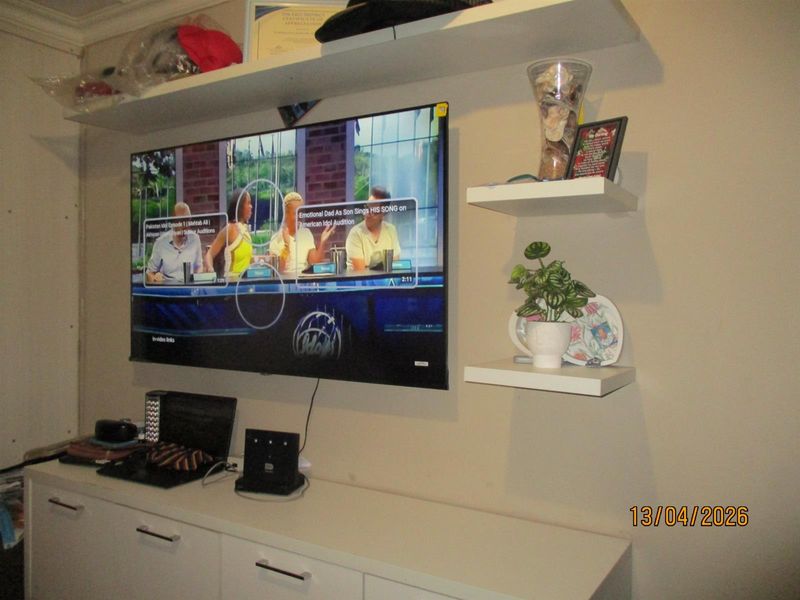 A living room wall featuring built-in white cabinetry and floating shelves, providing functional storage and display space.