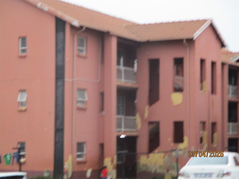 Exterior view of a multi-story residential building showing significant wear to the exterior paint and facade finishes.