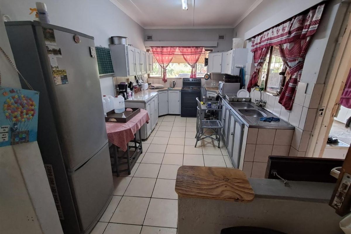 A functional kitchen featuring tiled flooring, built-in cabinetry, a double-basin sink, and a freestanding stove, offering a practical layout for daily meal preparation.