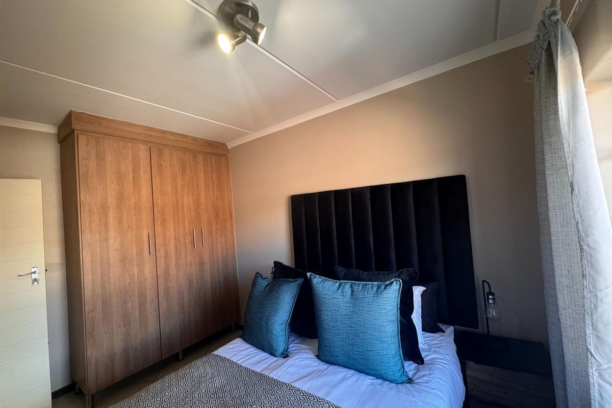 A well-maintained bedroom featuring a large built-in wooden wardrobe and modern ceiling spotlighting, offering a clean and functional living space.