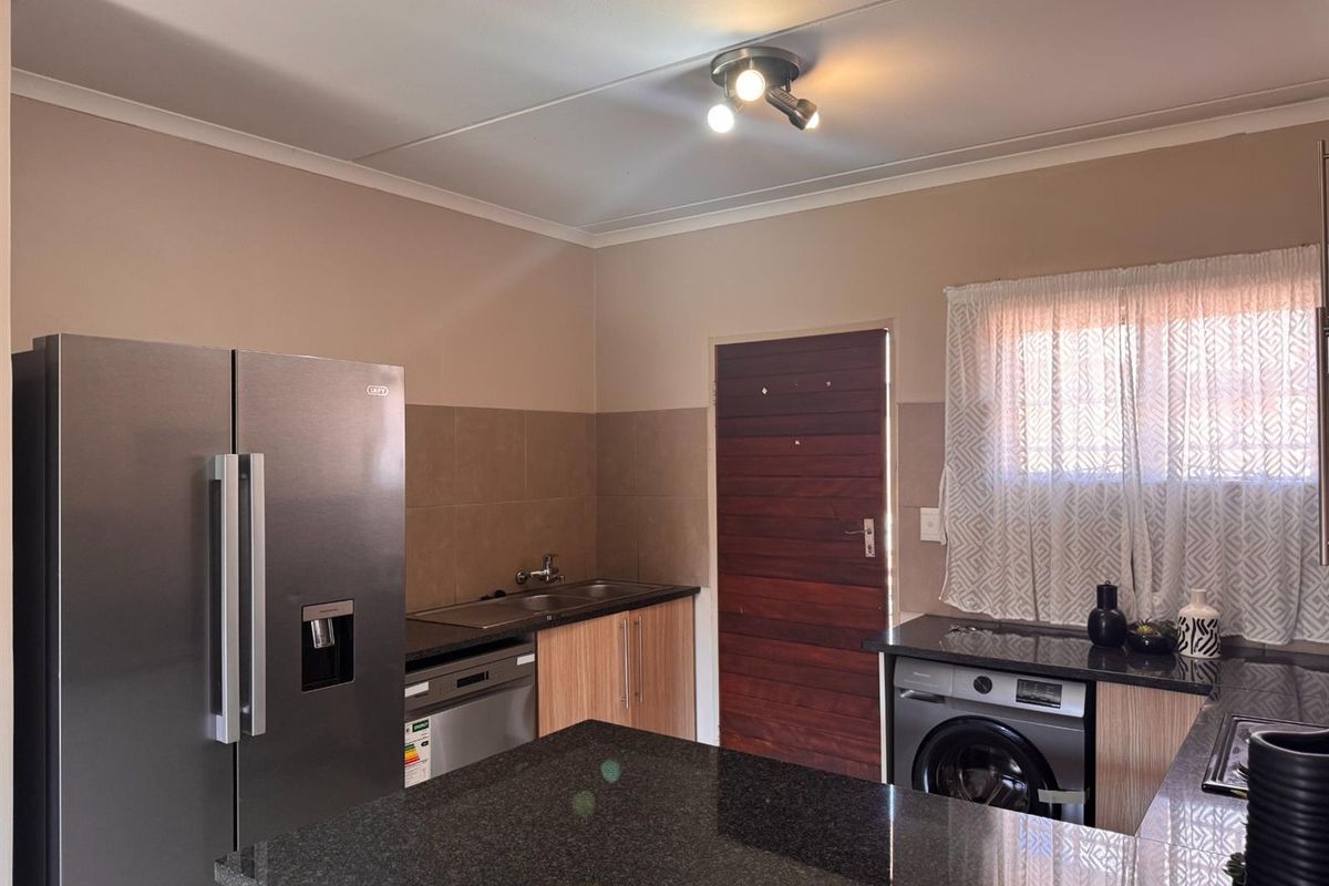 A functional kitchen featuring granite countertops, built-in cabinetry, a double sink, and a tiled backsplash, providing a practical and well-maintained workspace.