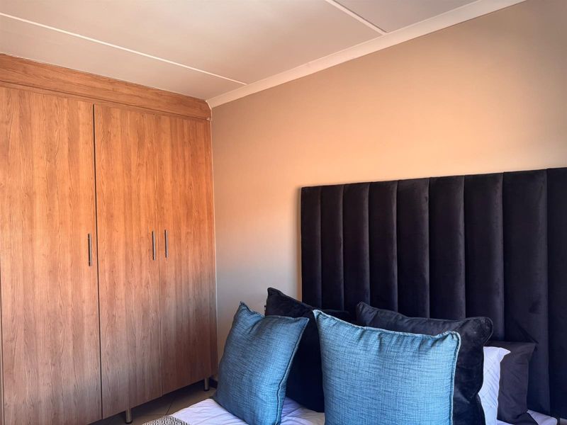 A bedroom featuring a built-in wooden wardrobe with clean lines and neutral wall finishes.