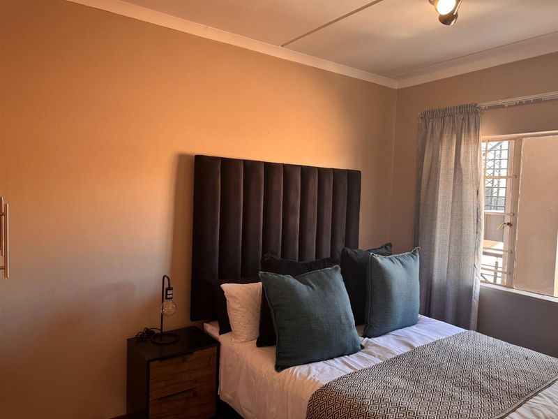 A cozy bedroom featuring neutral wall tones, a window with security bars, and classic coving detail.