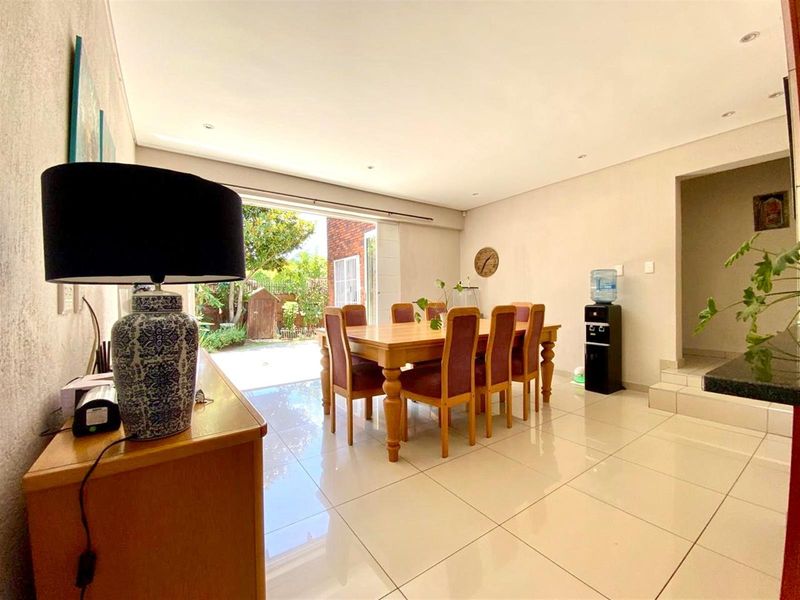 Spacious dining area featuring polished tile flooring, recessed lighting, and large sliding glass doors providing direct access to the outdoor patio and garden.