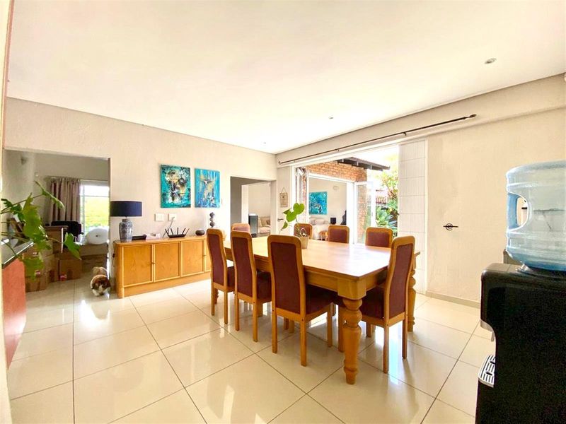 Open-plan dining area featuring large format floor tiles, recessed lighting, and seamless access to the outdoor patio through sliding glass doors.