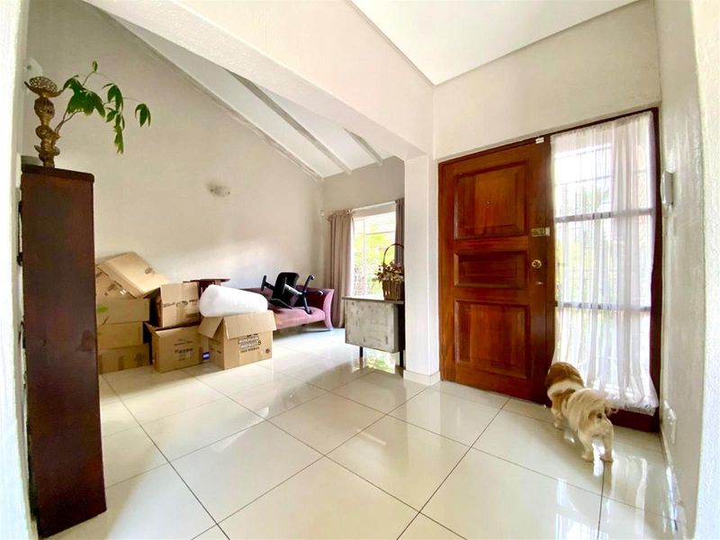 Bright entrance hall featuring tiled flooring, exposed beam ceilings, and a solid wood front door, providing a welcoming transition into the home.