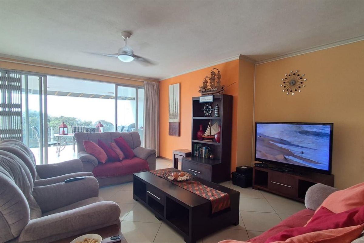 Spacious living room featuring tiled flooring, a ceiling fan, and large sliding glass doors providing access to an outdoor balcony area.