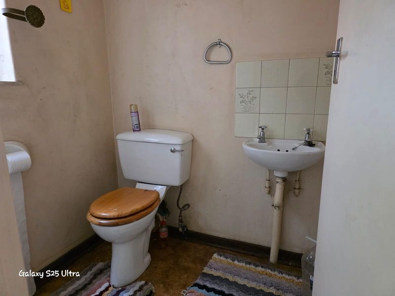 A compact guest bathroom featuring a standard toilet and a small wall-mounted basin with tiled splashback.