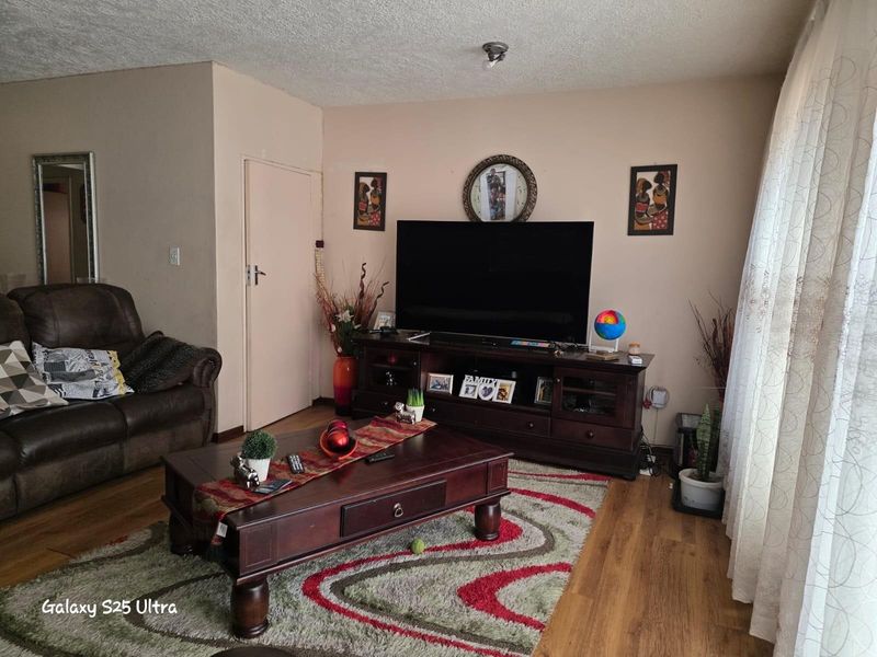 A comfortable living room featuring laminate flooring, neutral wall tones, and a standard layout suitable for relaxation.