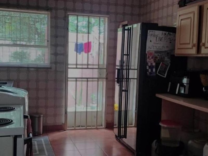 A functional kitchen featuring tiled walls, built-in cabinetry, and a direct access door leading to the exterior.