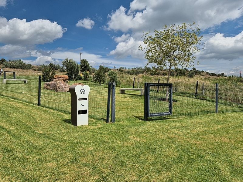 A well-maintained outdoor garden area featuring wire mesh fencing, a concrete bench, and a dedicated waste disposal station.