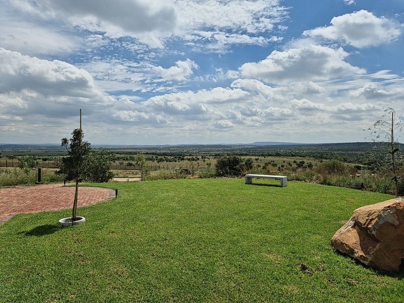 A scenic view of the surrounding landscape featuring a well-maintained lawn, brick paving, and open horizon.