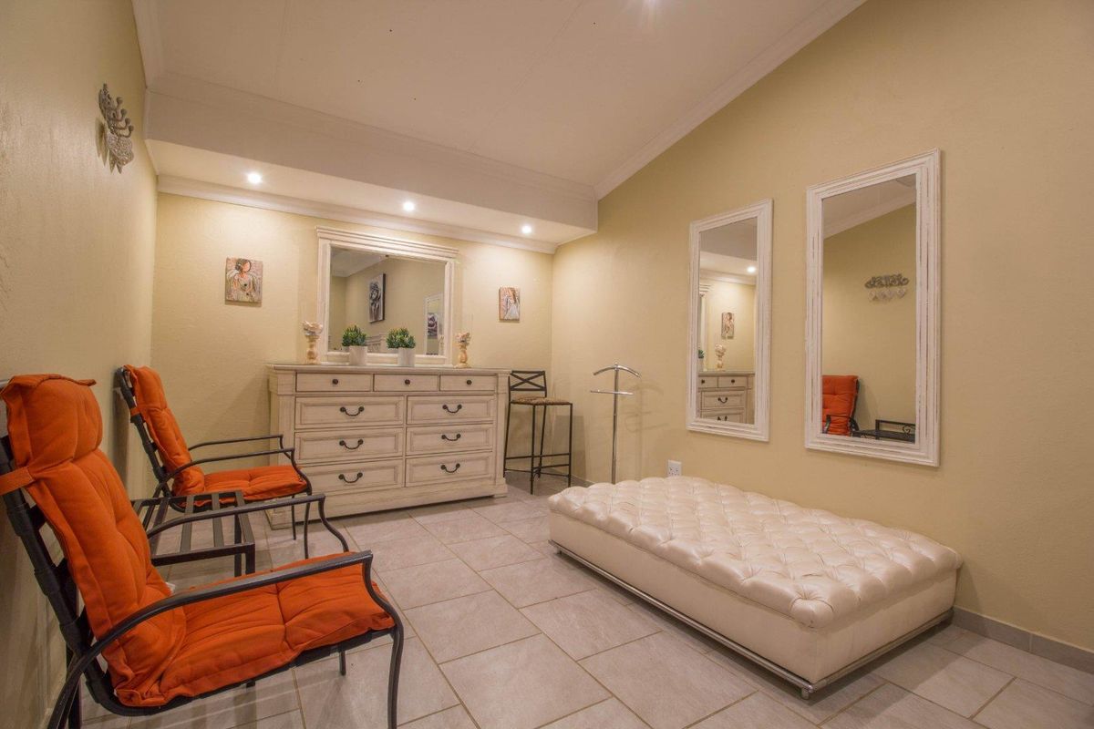 A well-lit interior space featuring tiled flooring, recessed ceiling lighting, and wall-mounted mirrors, suitable for use as a waiting area or lounge.