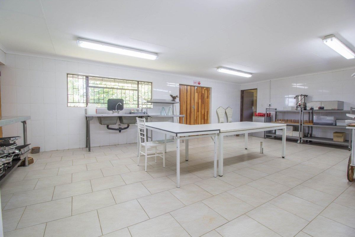 A commercial kitchen space featuring tiled walls, industrial-style double sink, fluorescent lighting, and durable floor tiling suitable for food preparation or utility use.