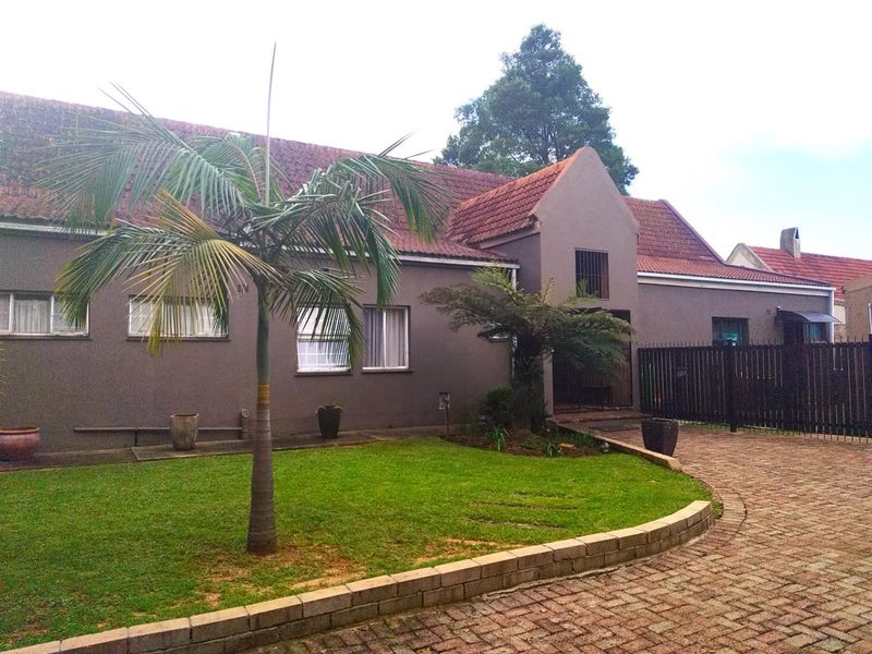 Front view of a single-story house featuring a tiled roof, paved driveway, and a landscaped front garden area.