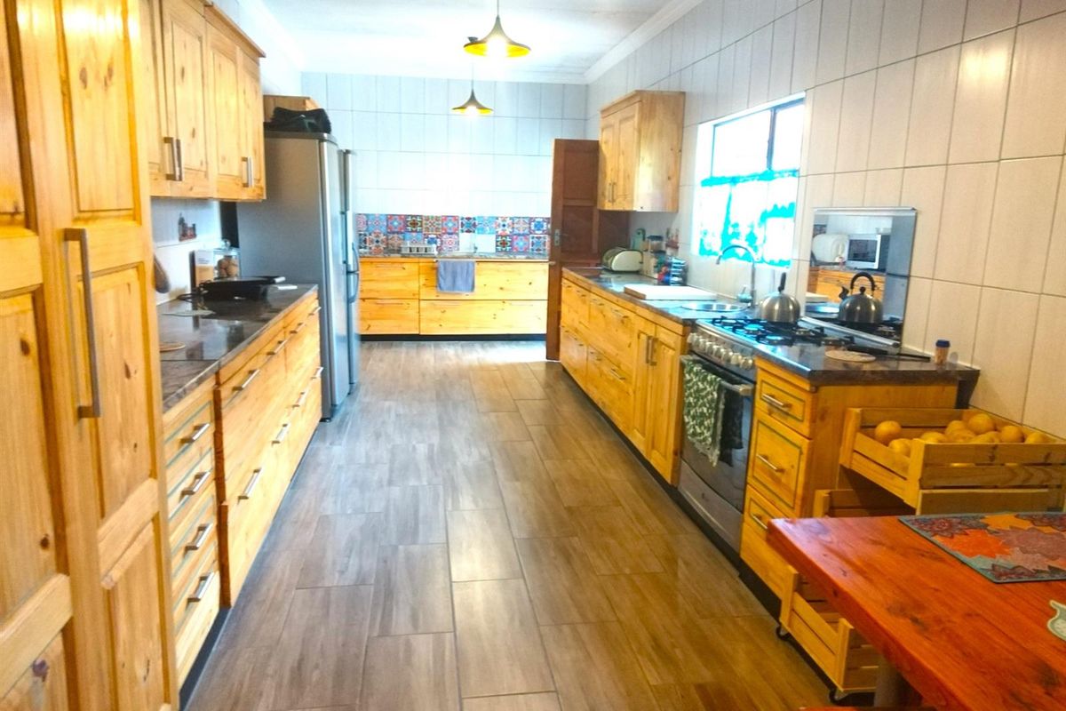 Spacious galley-style kitchen featuring extensive wooden cabinetry, tiled splashbacks, integrated gas stove, and durable floor tiling throughout.