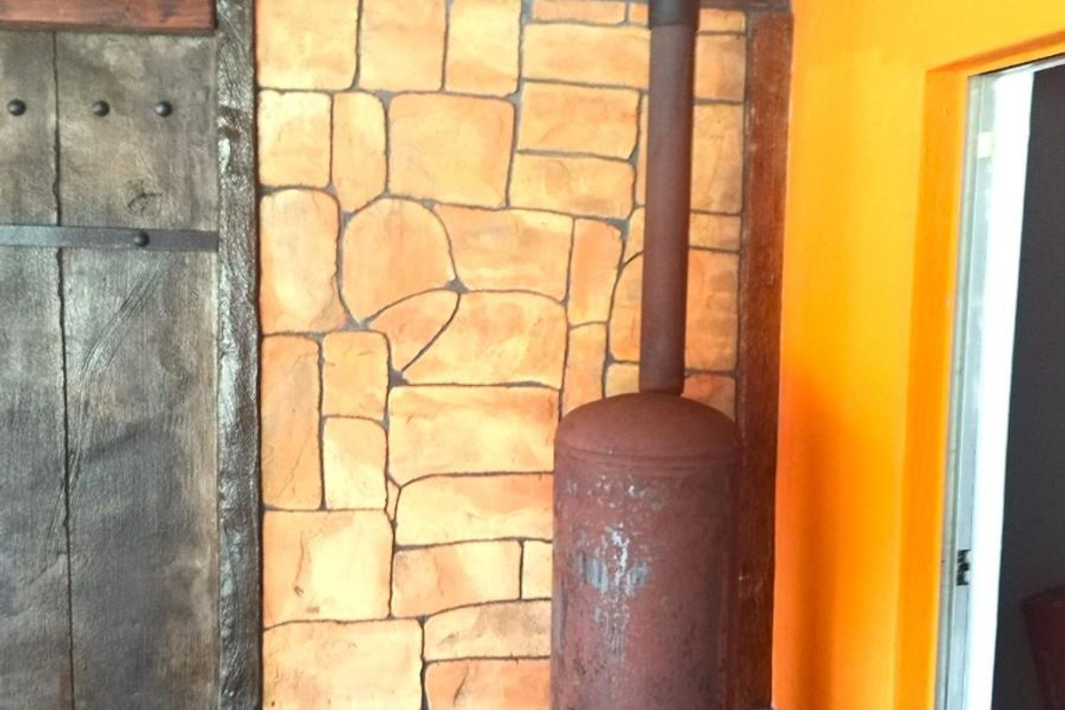 A rustic living area feature wall with stone cladding and a vintage metal wood-burning fireplace unit.