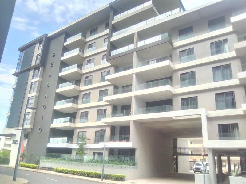 Modern multi-story apartment building facade featuring glass-fronted balconies and a covered ground-level entrance.