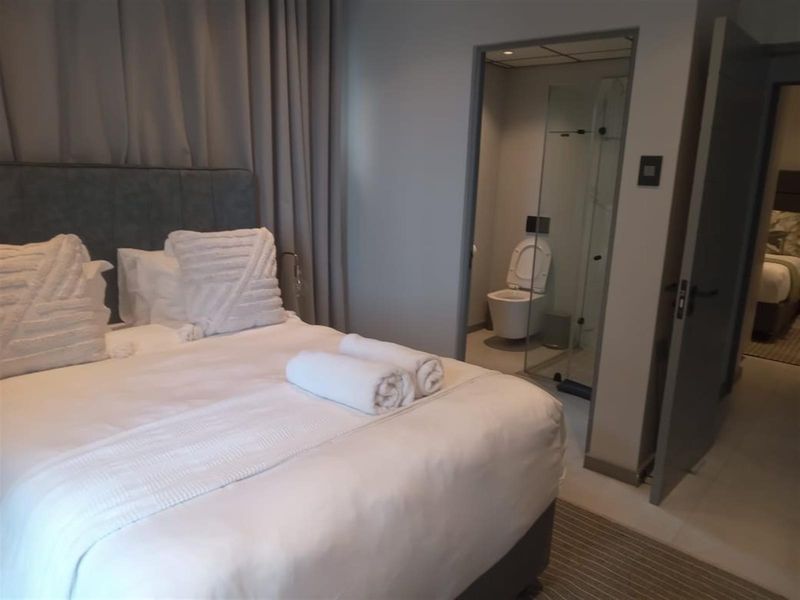 A well-maintained bedroom featuring an en-suite bathroom with a modern glass shower enclosure and wall-mounted toilet.