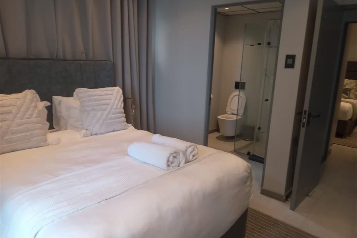 A well-maintained bedroom featuring an en-suite bathroom with a modern glass shower enclosure and wall-mounted toilet.