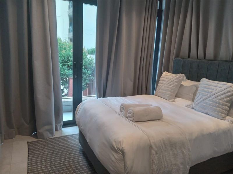 A well-maintained bedroom featuring tiled flooring and a large sliding glass door providing access to an outdoor balcony area.