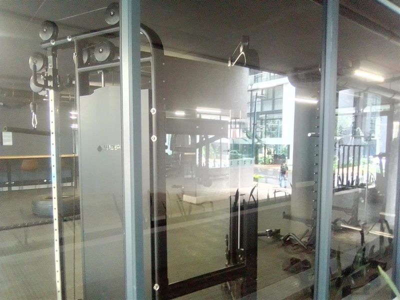 A view through a glass partition into a modern gym facility featuring integrated fitness equipment and recessed lighting.