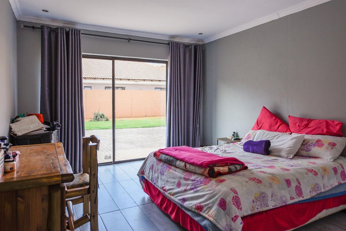 Spacious bedroom featuring tiled flooring and a large sliding glass door providing direct access to the rear garden area.