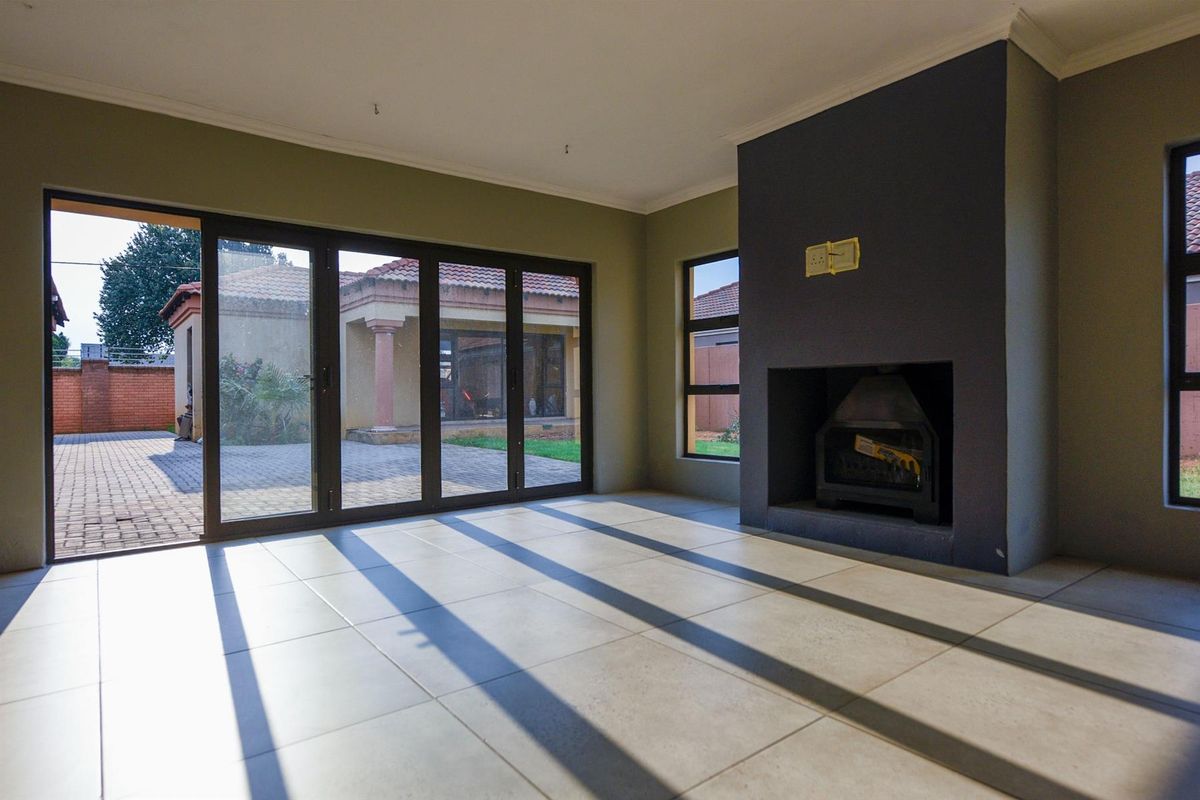 Spacious living room featuring large sliding glass doors, tiled flooring, and a built-in fireplace, offering direct access to the outdoor patio area.