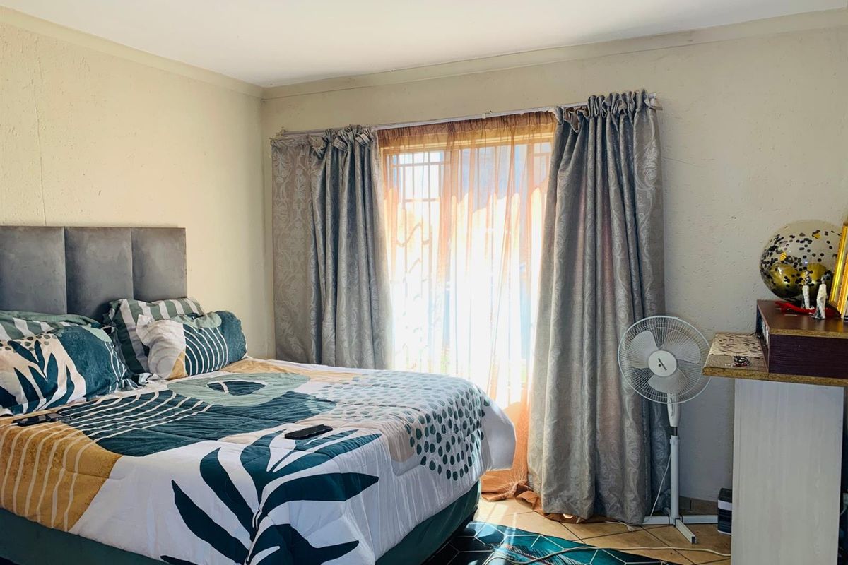 A bedroom featuring tiled flooring and a window with curtain tracks, providing natural light and a functional living space.