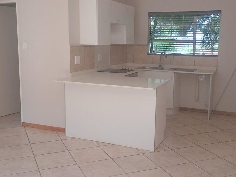 Open plan kitchen area featuring white built-in cabinetry, tiled flooring, and a breakfast nook, presenting a clean and functional space.