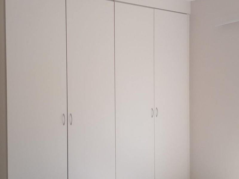 A clean, empty bedroom featuring neutral walls and ample built-in cupboard storage space.