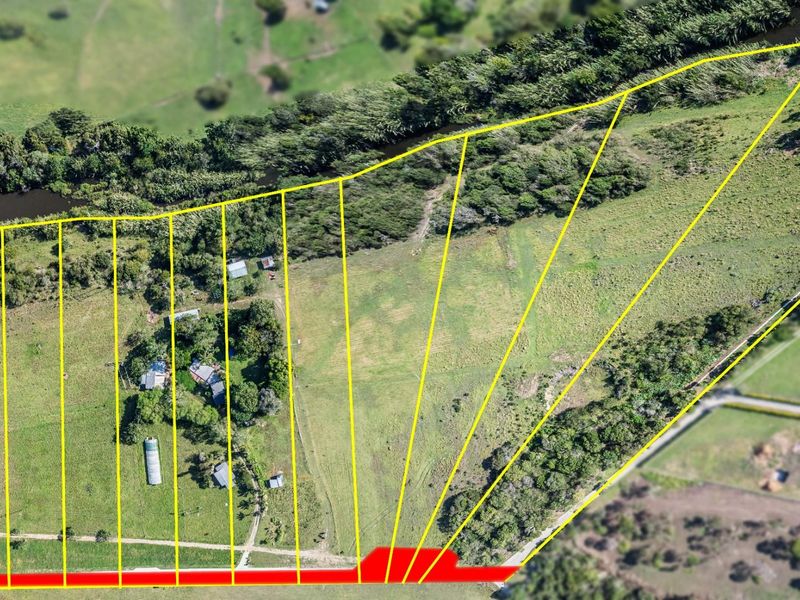 Aerial view of a large vacant residential land parcel featuring natural vegetation, open grassy areas, and bordering a water feature.