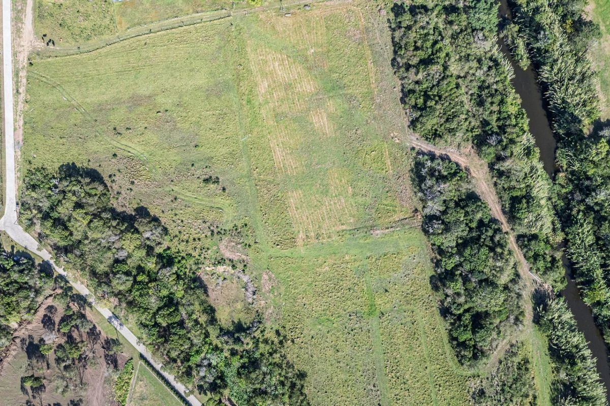 Aerial view of a large, vacant residential land parcel featuring cleared pasture, natural vegetation, and river frontage.