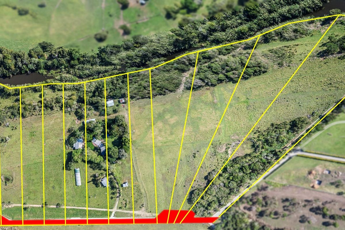 Aerial view of a large vacant residential land parcel featuring defined boundaries, natural vegetation, and water frontage.