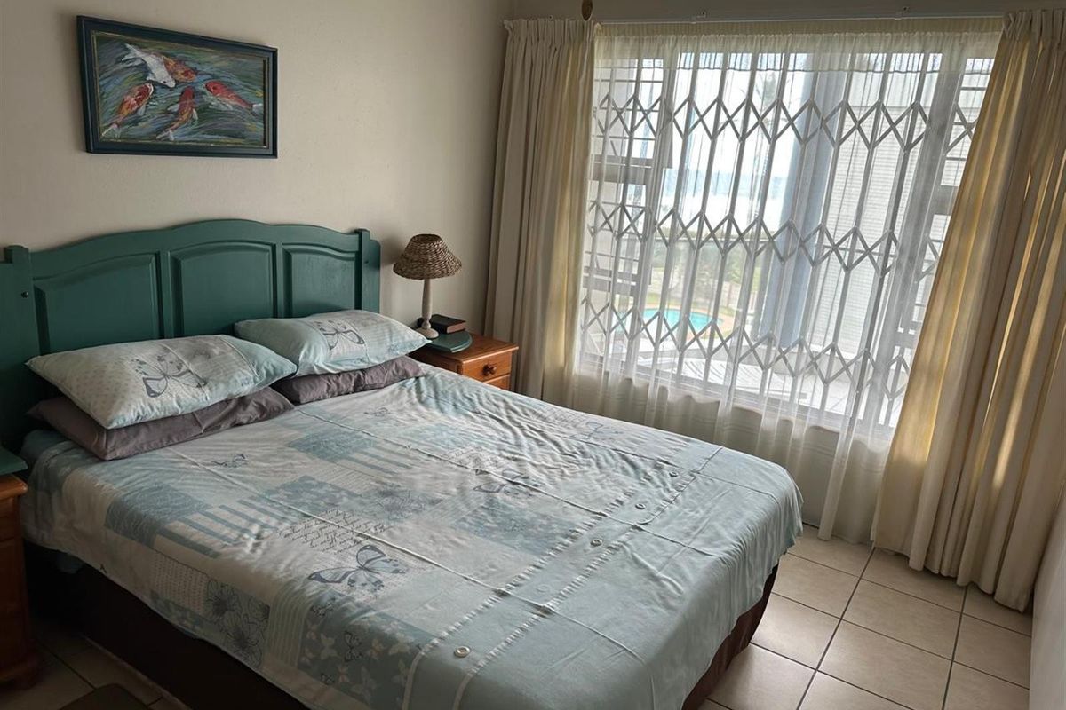 A bedroom featuring tiled flooring, a large window with security gate, and neutral wall finishes.