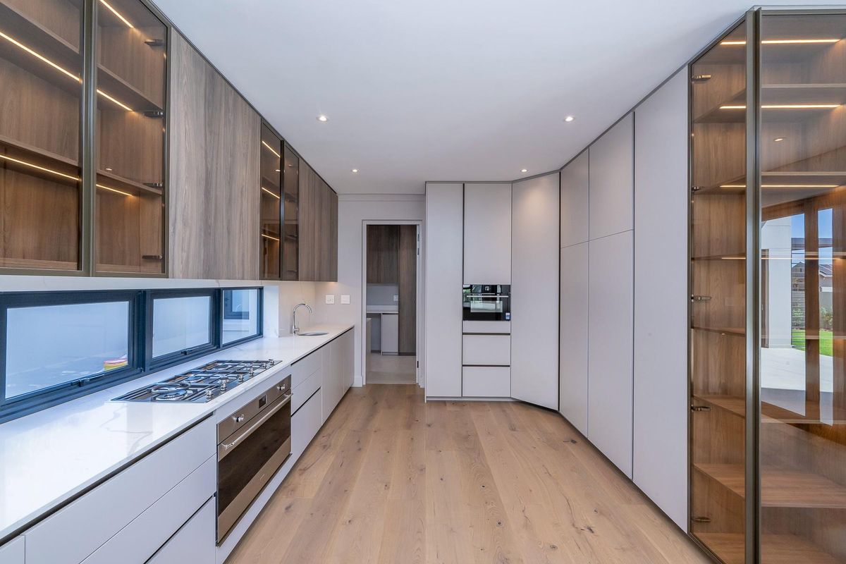 Modern kitchen featuring sleek cabinetry, integrated oven and gas hob, stone countertops, and timber flooring with recessed lighting.