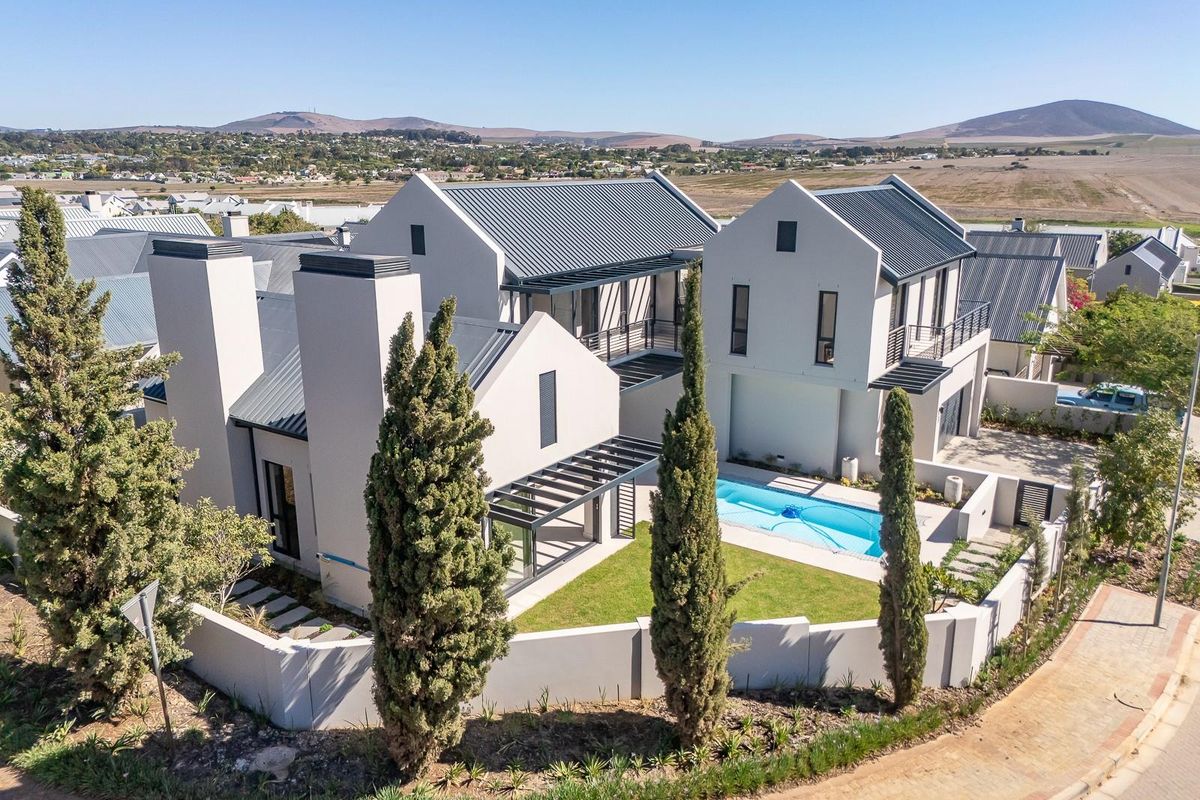 Aerial view of a modern double-story residence featuring a swimming pool, landscaped garden, metal roof, and contemporary architectural design.