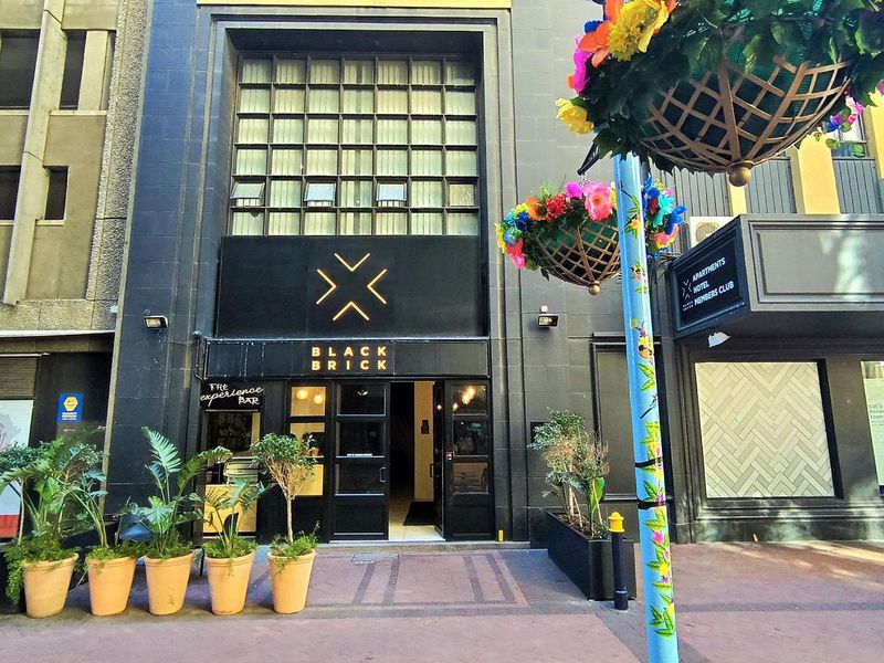 Street-level view of the Black Brick apartment building entrance, featuring a modern black facade and prominent signage.