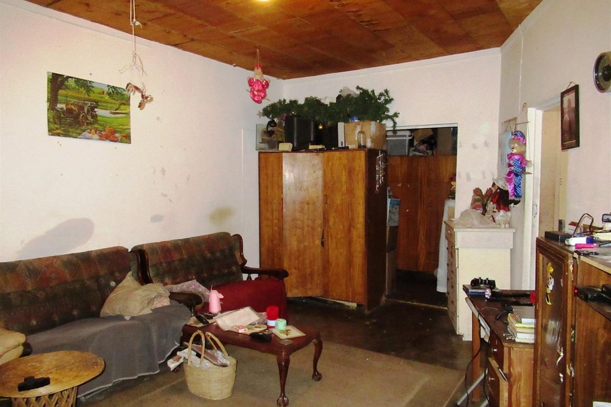 A living room area featuring a wooden panelled ceiling and basic interior finishes, requiring cosmetic updates.