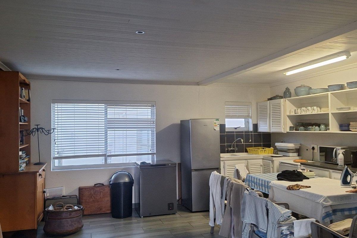 A functional kitchen area featuring built-in cabinetry, tiled backsplash, and tiled flooring, offering a practical layout for daily meal preparation.