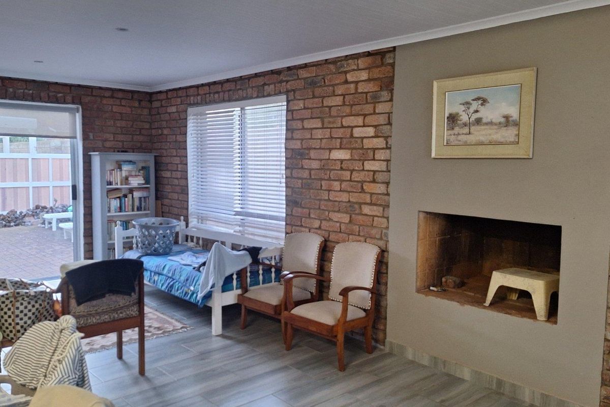 Living room featuring a rustic exposed brick feature wall, built-in fireplace, and sliding glass doors providing access to the outdoor patio area.