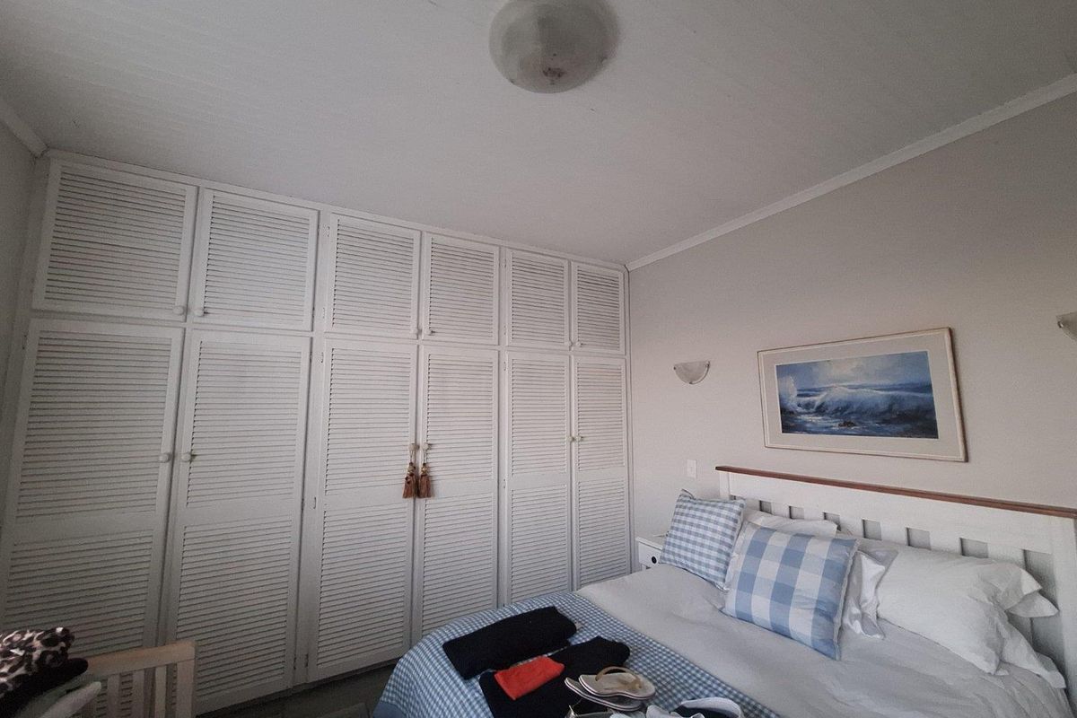 A bedroom featuring floor-to-ceiling white louvered built-in cupboards and wall-mounted lighting fixtures.