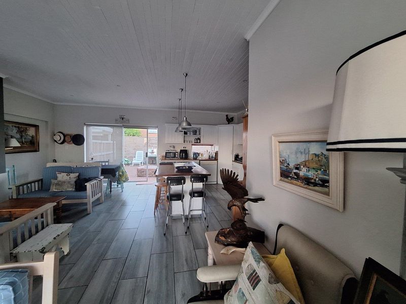 Open-plan living area featuring a modern kitchen with a central island, tiled flooring, and sliding glass doors leading to the rear patio.